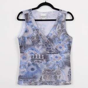 May include: A sleeveless blue and gray tie-dye top with a V-neck and a wrap-style design. The top features a paisley print and the text "Fashion Bug" on the label.