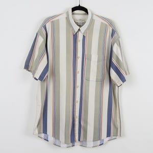 May include: Short-sleeved button-down shirt with vertical stripes in white, blue, green, and red. The shirt has a chest pocket and a collar. The shirt is hanging on a black hanger against a white background.