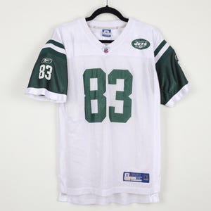 May include: A white Reebok New York Jets football jersey featuring the number 83 in dark green on the front and sleeves. The jersey has dark green shoulder panels with white stripes, a V-neck collar, and an NFL logo patch at the neckline.