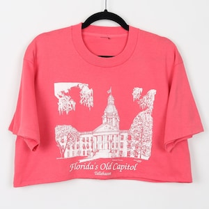 May include: A pink cropped t-shirt with a white graphic of the Florida Old Capitol building in Tallahassee.