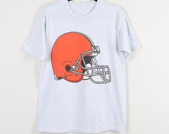 May include: A light gray t-shirt featuring a large orange football helmet graphic. The helmet has a black stripe and a silver face mask. The shirt is hanging on a black hanger.