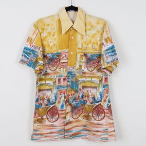 May include: A short-sleeved button-up shirt with a unique print featuring horse-drawn carriages and figures in a city scene. The shirt has a yellow collar and a button-down front. The print includes shades of yellow, blue, red, and brown.