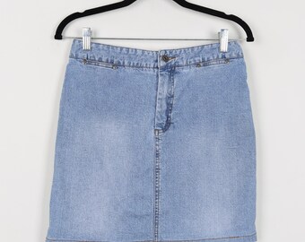 May include: Light blue denim skirt hanging on a black hanger. The skirt has a classic five-pocket design, a button and zipper closure, and small silver rivets along the waistband. The skirt is made of a medium-wash denim fabric.