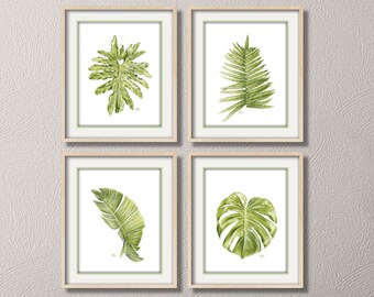 May include: Four framed watercolor paintings of green tropical leaves, displayed on a white wall above a light beige sofa with green throw pillows.