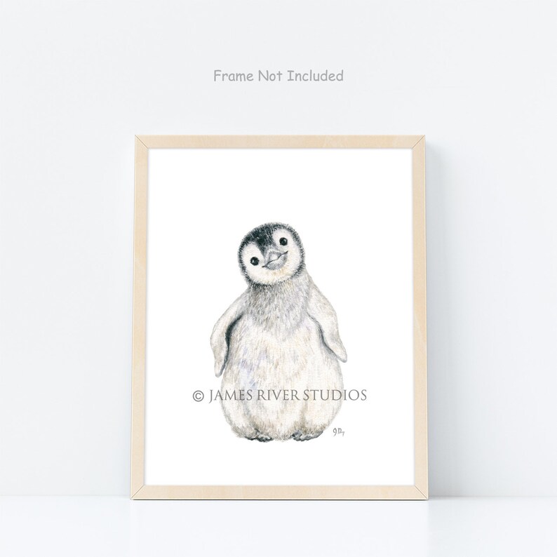 May include: A framed print featuring a watercolor illustration of a baby penguin. The penguin has a black head and back, with a white belly and fluffy gray feathers. The print is in a light wood frame. Text on the print reads "Frame Not Included" and "&copy; JAMES RIVER STUDIOS".