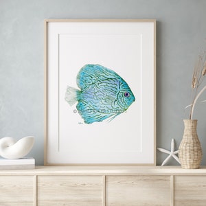 May include: A watercolor painting of a blue and green discus fish with a red eye. The fish is swimming to the right and has a white background.