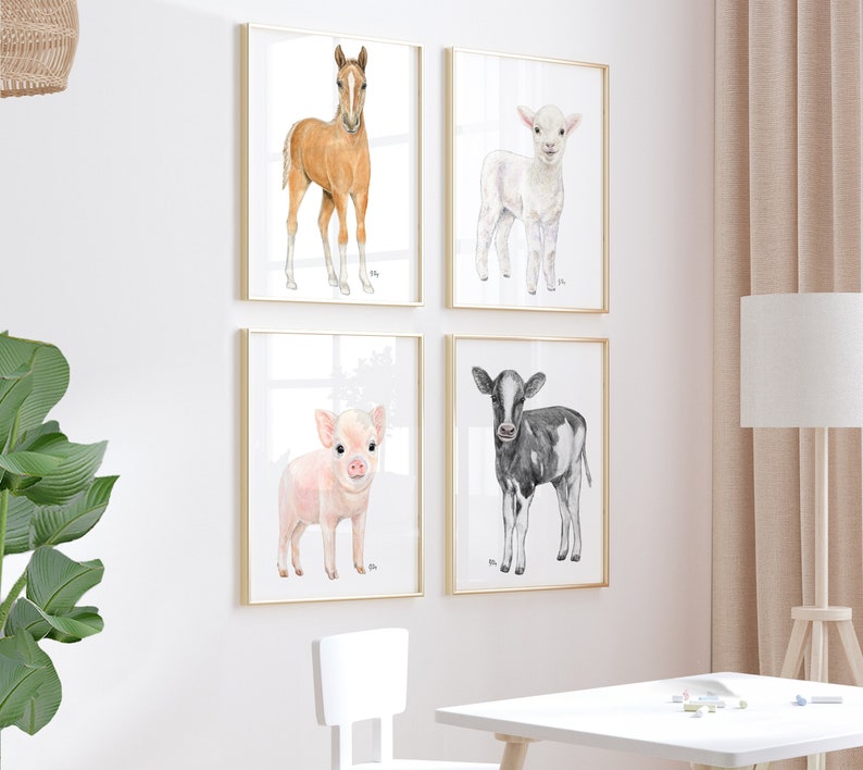 Puede incluir: Conjunto de cuatro estampas de animales en acuarela que representan un potro marr&oacute;n, un cordero blanco, un lech&oacute;n rosado y un ternero blanco y negro. Cada estampa est&aacute; enmarcada en un marco dorado y tiene un fondo blanco.