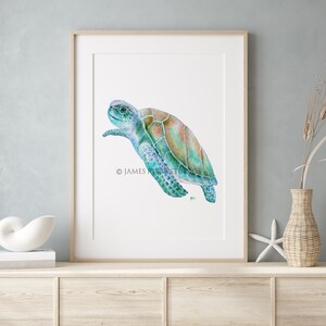 Op de afbeelding: Een aquarel schilderij van een zeeschildpad die in de oceaan zwemt. De schildpad is geschilderd in tinten blauw, groen en bruin. De achtergrond is wit.