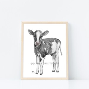 Puede incluir: Dibujo a l&aacute;piz en blanco y negro de un ternero de pie sobre un fondo blanco. El ternero tiene la nariz y las pezu&ntilde;as negras. El dibujo est&aacute; enmarcado en un marco de madera claro.