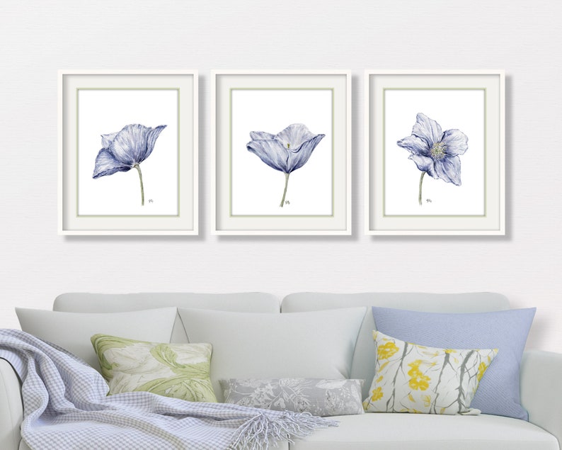 Puede incluir: Conjunto de tres impresiones de acuarela enmarcadas que presentan flores azules con acentos blancos. Las impresiones est&aacute;n en marcos blancos con un tapete verde claro.