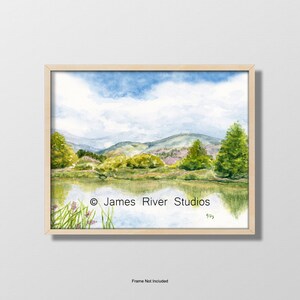 May include: Watercolor painting of a landscape with a lake, mountains, and trees. The sky is blue with white clouds. The painting is framed in a light wood frame. &copy; James River Studios 993