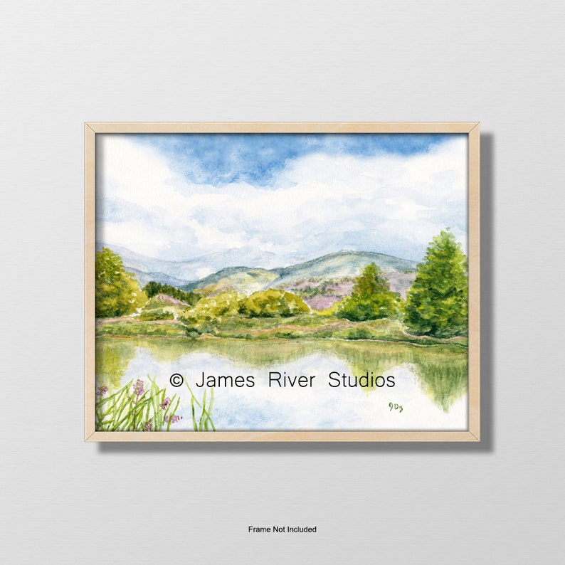 May include: Watercolor painting of a landscape with a lake, mountains, and trees. The sky is blue with white clouds. The painting is framed in a light wood frame. &copy; James River Studios 993