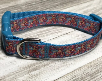 May include: A blue dog collar with a colorful floral pattern. The collar has a silver buckle and is made of durable nylon.