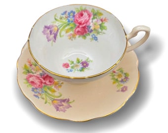 May include: A vintage teacup and saucer set with a floral pattern. The cup and saucer are white with a gold trim. The floral pattern features pink, purple, and blue flowers.