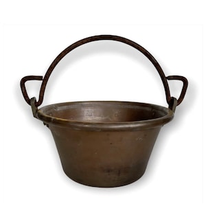 May include: A vintage copper pot with a rusty iron handle. The pot is round and has a flared lip. The handle is attached to the pot with two metal rings.