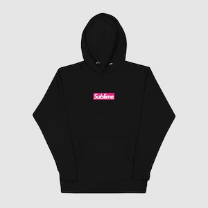 May include: Black hoodie with a pink rectangular logo that reads "Sublime" in white lettering. The hoodie has a hood and a front pocket. The garment is made of a soft material.