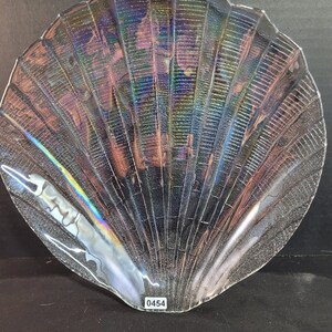 May include: A clear glass seashell-shaped serving dish with iridescent detailing. The dish has a textured surface and a number "0454" printed on the bottom.