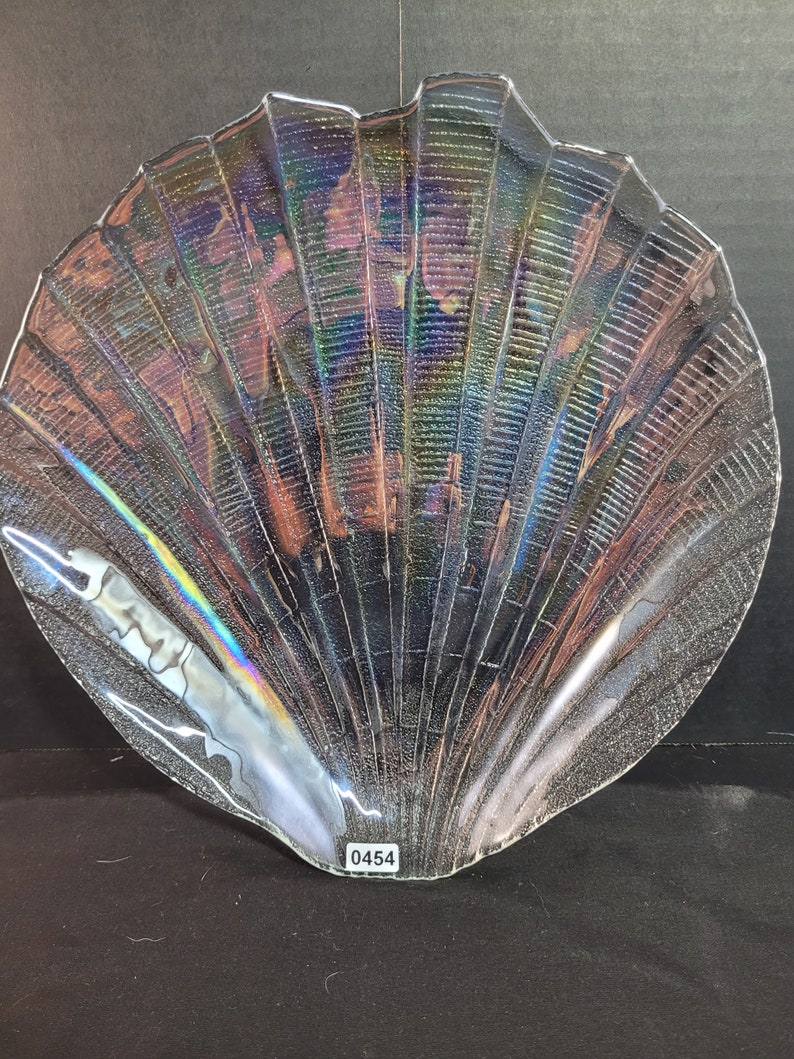 May include: A clear glass seashell-shaped serving dish with iridescent detailing. The dish has a textured surface and a number "0454" printed on the bottom.