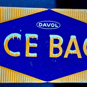 May include: Rectangular box with the words "ICE BAG" in large, yellow, icy letters on a blue diamond-shaped background. The box has a gold background with white snowflakes and the brand name "DAVOL".