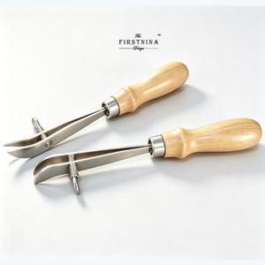 May include: Two leather craft edge creasers with light-colored wooden handles and silver-colored metal tips. Each tool features a metal adjustment screw on the side of the fork. The text "The FIRSTNINA Design" is printed in black above the tools.