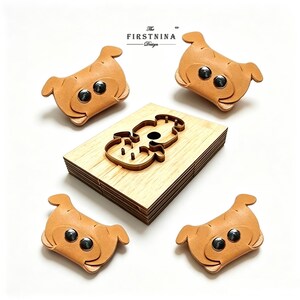 May include: Four tan leather animal-shaped drawer pulls with black metal rivets for eyes, arranged around a rectangular wooden cutting die featuring a central cutout of the same animal shape, with the text The FIRSTNINA Design printed above.