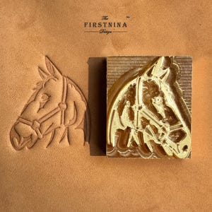 May include: A brass metal stamp featuring a horse head design with a bridle, positioned next to its embossed impression on a tan leather surface. The text The FIRSTNINA Design is printed in black above the stamp and its leather imprint.