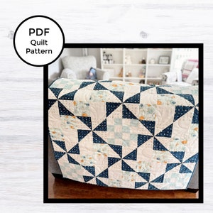 Peut inclure: Un patron de courtepointe PDF pour une courtepointe avec un motif de moulin à vent bleu marine et blanc. La courtepointe est faite avec un tissu floral et a un fond blanc.