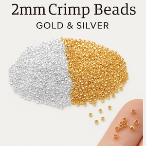Puede incluir: Primer plano de cuentas de crimpado de 2 mm en oro y plata. La imagen muestra una gran pila de cuentas doradas junto a una pila de cuentas plateadas. El texto "2mm Crimp Beads GOLD & SILVER" está en la parte superior de la imagen.