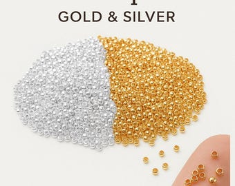 May include: Image of 2mm crimp beads in gold and silver. A large quantity of gold beads is next to a pile of silver beads. The text "2mm Crimp Beads GOLD & SILVER" is at the top of the image.