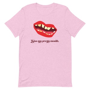 May include: Pink t-shirt with a graphic of a red mouth with yellow teeth and the text "Kiss my pretty mouth."