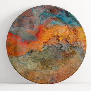 May include: Round wall art with a swirling abstract design in shades of orange, brown, blue, and gray.