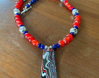 Red, silver, and blue necklace with Fordite pendant
