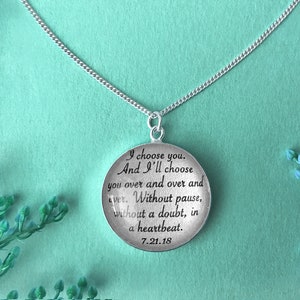 May include: Silver necklace with a round pendant that reads "I choose you. And I'll choose you over and over and over. Without pause, without a doubt, in a heartbeat. 7.21.18"