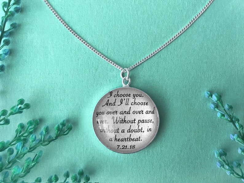 May include: Silver necklace with a round pendant that reads "I choose you. And I'll choose you over and over and over. Without pause, without a doubt, in a heartbeat. 7.21.18"