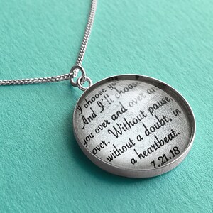 May include: A silver necklace with a round pendant that says "I choose you and I'll choose you over and over and over. Without pause without a doubt, in a heartbeat. 7.21.18"