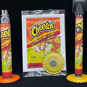 May include: Two red and yellow vape pens with a Cheetos Flamin' Hot Limon Crunchy bag and a yellow and gold cap. The vape pens have a Cheetos Flamin' Hot Limon Crunchy design.