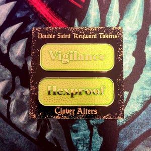 May include: Two double-sided keyword tokens with the words "Vigilance" and "Hexproof" in a green and gold color scheme. The tokens are on a black background with the text "Double Sided Keyword Tokens" and "Clover Alters".