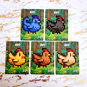 May include: Five illustrated cards with a pixelated design of different birds. Each card has the word "BIRD" at the top and "2/2" at the bottom. The birds are a blue bird, a black bird, a yellow bird, a brown bird, and a white bird.