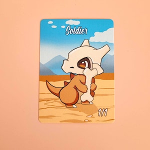 May include: A trading card featuring a cartoon character with a bone helmet and a bone in its hands. The card has a blue sky background with the word "Soldier" and the number "1/1". The character is brown and white.