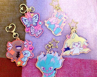 May include: Collection of colorful acrylic keychains with gold-colored hardware. Designs include butterflies, geometric shapes, and cartoon characters. Each keychain has a star-shaped charm and a heart-shaped clasp.