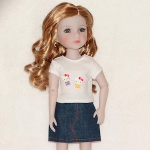 May include: A doll with long, wavy auburn hair, wearing a white t-shirt with two Hello Kitty designs and a denim skirt. The skirt has red stitching. The doll has blue eyes and is posed against a white background.