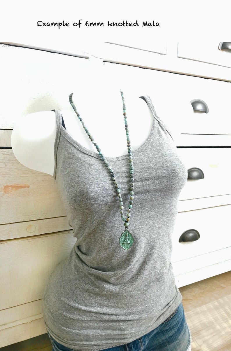 May include: A 6mm knotted mala necklace featuring small, mottled blue-green beads and a translucent, teardrop-shaped pendant with an embossed figure. The text 'Example of 6mm knotted Mala' is visible at the top of the image.