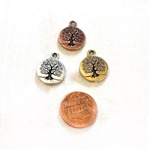 Puede incluir: Tres abalorios redondos de metal con un dise&ntilde;o de &aacute;rbol de la vida. Los abalorios son de plata, oro y cobre.