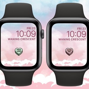 May include: Two black Apple Watch Series 7 smartwatches with pink and blue watercolor backgrounds. The watch faces display the time as 10:09, the date as FRI 23, and the moon phase as "WANING CRESCENT". One watch face has a candy heart with the text "TRUE LOVE" and the other has a candy heart with the text "CUTIE PIE".