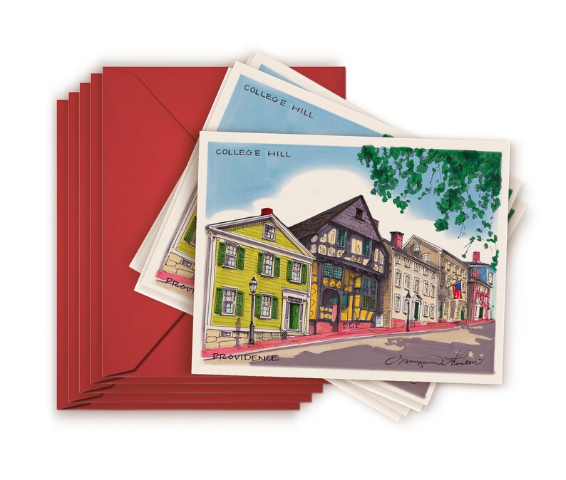 May include: A stack of red envelopes with white postcards inside. The postcards feature a watercolor illustration of a row of colorful historic buildings in Providence, Rhode Island. The text on the postcards reads "College Hill, Providence".