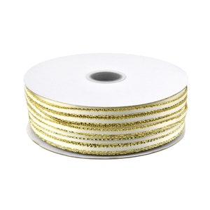 May include: A spool of white satin ribbon with gold metallic trim. The ribbon is wound around a white cardboard spool.