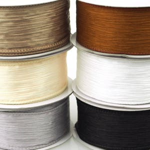 May include: Six spools of ribbon in various colors, including brown, beige, white, gray, and black. The ribbon is a silky, textured material.