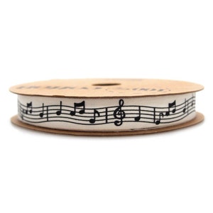 May include: A spool of white cotton ribbon with black musical notes printed on it.