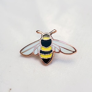 May include: A gold-toned bee pin with black and yellow stripes and white wings.