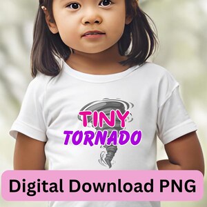 Puede incluir: Una camiseta blanca con un gráfico de tornado gris y blanco y el texto "Tiny Tornado" en letras rosas.